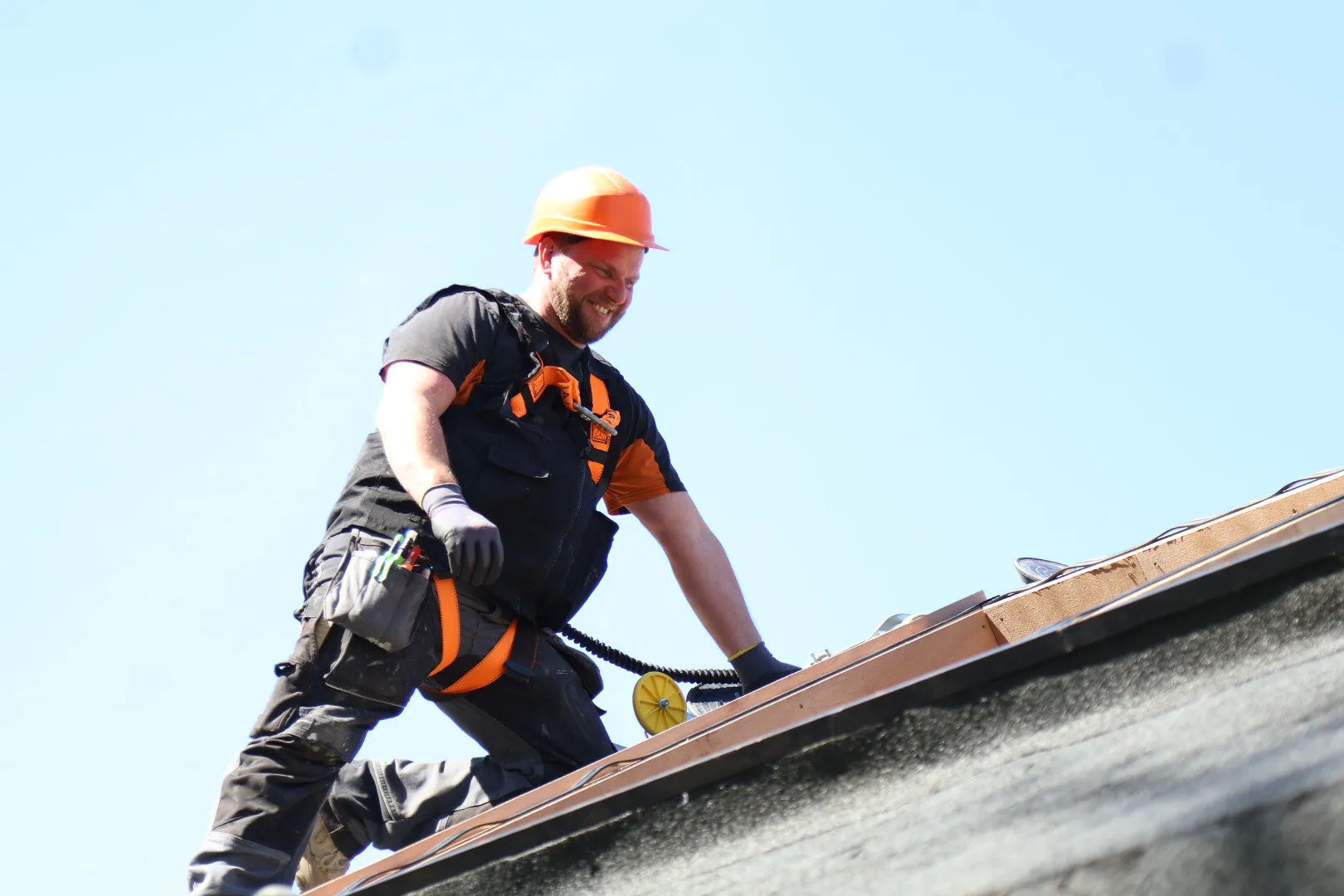 Vakman van Teerenstra met helm en valbeveiliging aan het werk op een dak